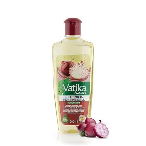 Flacon d’huile capillaire jaune à l’oignon rouge posé sur une pierre claire dans une salle de bain épurée.