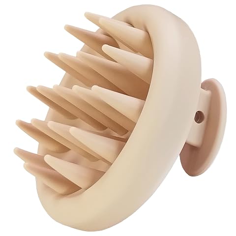 Brosse de massage du cuir chevelu en silicone beige posée sur une pierre claire dans une salle de bain