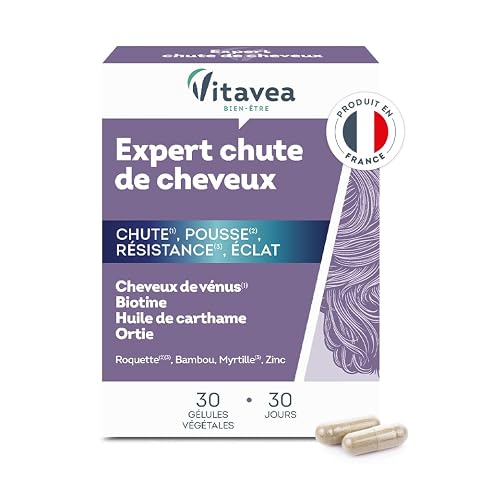 Boîte violette de complément capillaire posée sur une pierre claire dans une salle de bain épurée.