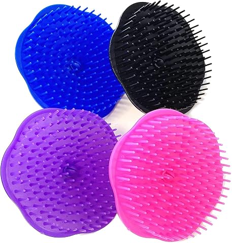 Quatre brosses rondes multicolores à picots posées sur une pierre claire dans une salle de bain épurée.