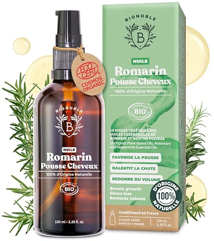 Flacon ambré d’huile capillaire au romarin posé sur une pierre claire avec quelques brins de romarin