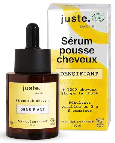 Flacon jaune de sérum capillaire posé sur une pierre claire dans une salle de bain épurée.